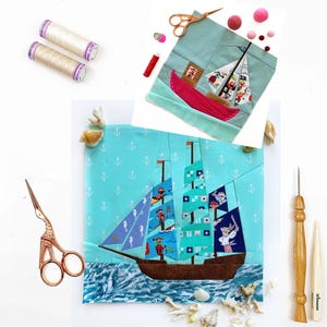 May include: Two colorful fabric patchwork ships with anchor details on a light blue background. The ships are surrounded by white anchors, seashells, and sewing supplies, including thread spools, scissors, and a needle.