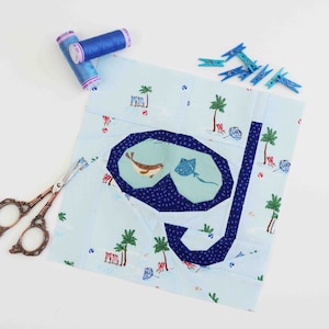 May include: A blue and white fabric block with a blue and white fabric scuba mask and snorkel design. The block is surrounded by blue clothespins and two spools of blue thread.