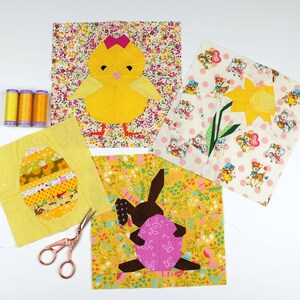 May include: A set of five fabric squares featuring different Easter-themed designs. The squares are made of yellow, white, and pink fabric with a variety of patterns. The designs include a chick, a bunny, an egg, and a daffodil.