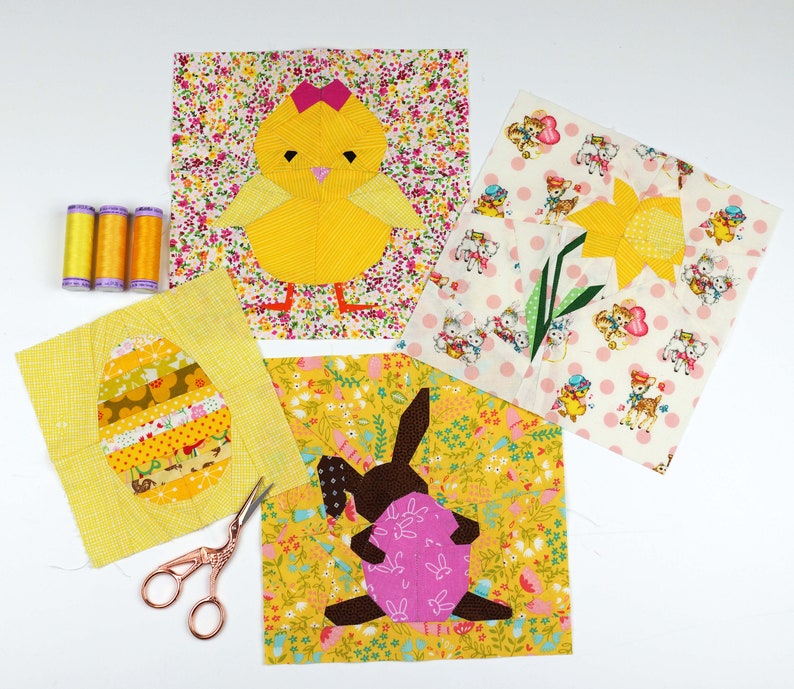 May include: A set of five fabric squares featuring different Easter-themed designs. The squares are made of yellow, white, and pink fabric with a variety of patterns. The designs include a chick, a bunny, an egg, and a daffodil.
