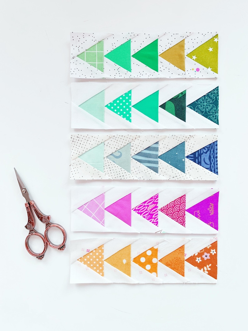 May include: Five rows of fabric triangles sewn together in a chevron pattern. Each row features a different color scheme, including green, blue, pink, and orange. The fabric triangles have various patterns, including polka dots, stripes, and floral prints.