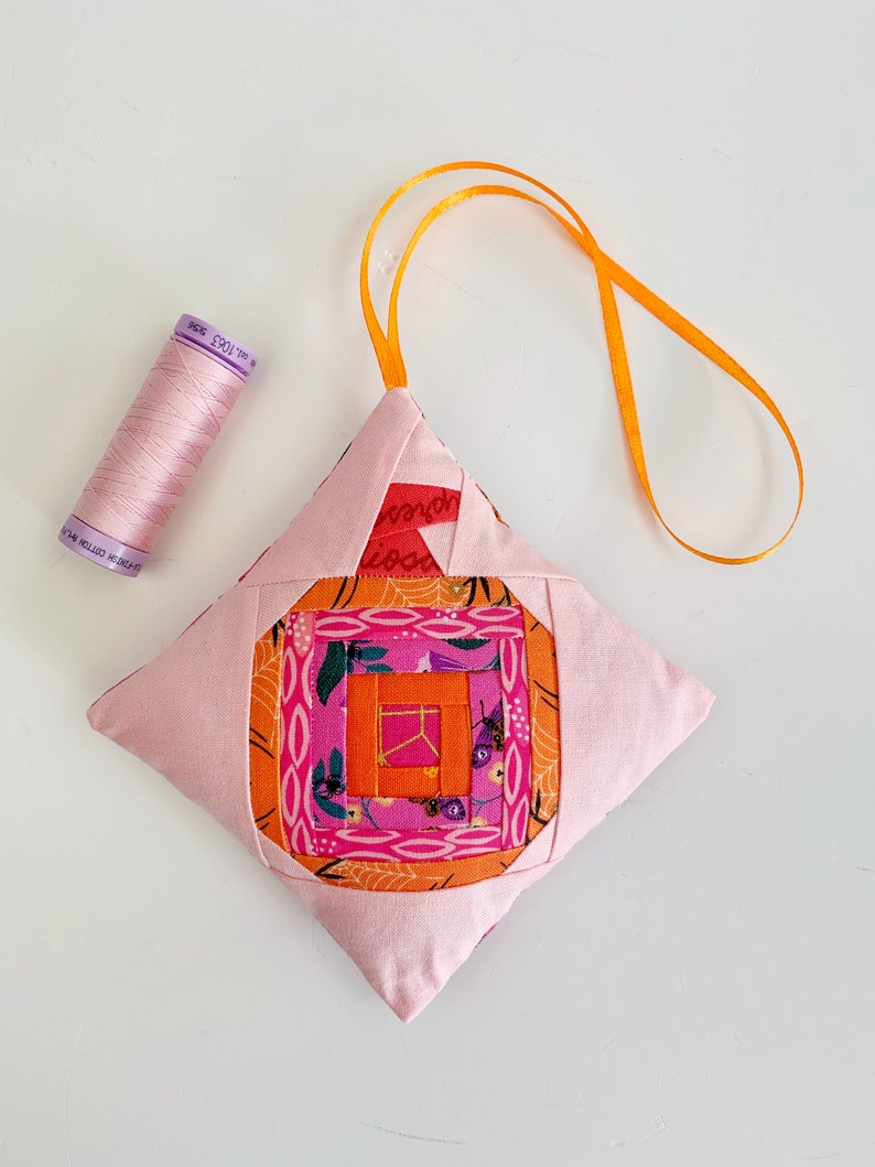 log cabin pumpkin ornament in pink and orange.log cabin pumpkin quilt block pattern in 5 different sizes, from 4x4 inch for ornaments to 6x6, 8x8, 10x10 and 12x12 inches for all sorts of amazing Halloween sewing projects. Use your favorite fabrics to fussy cut the center and turn these amazing beauties into your own pumpkin patch.