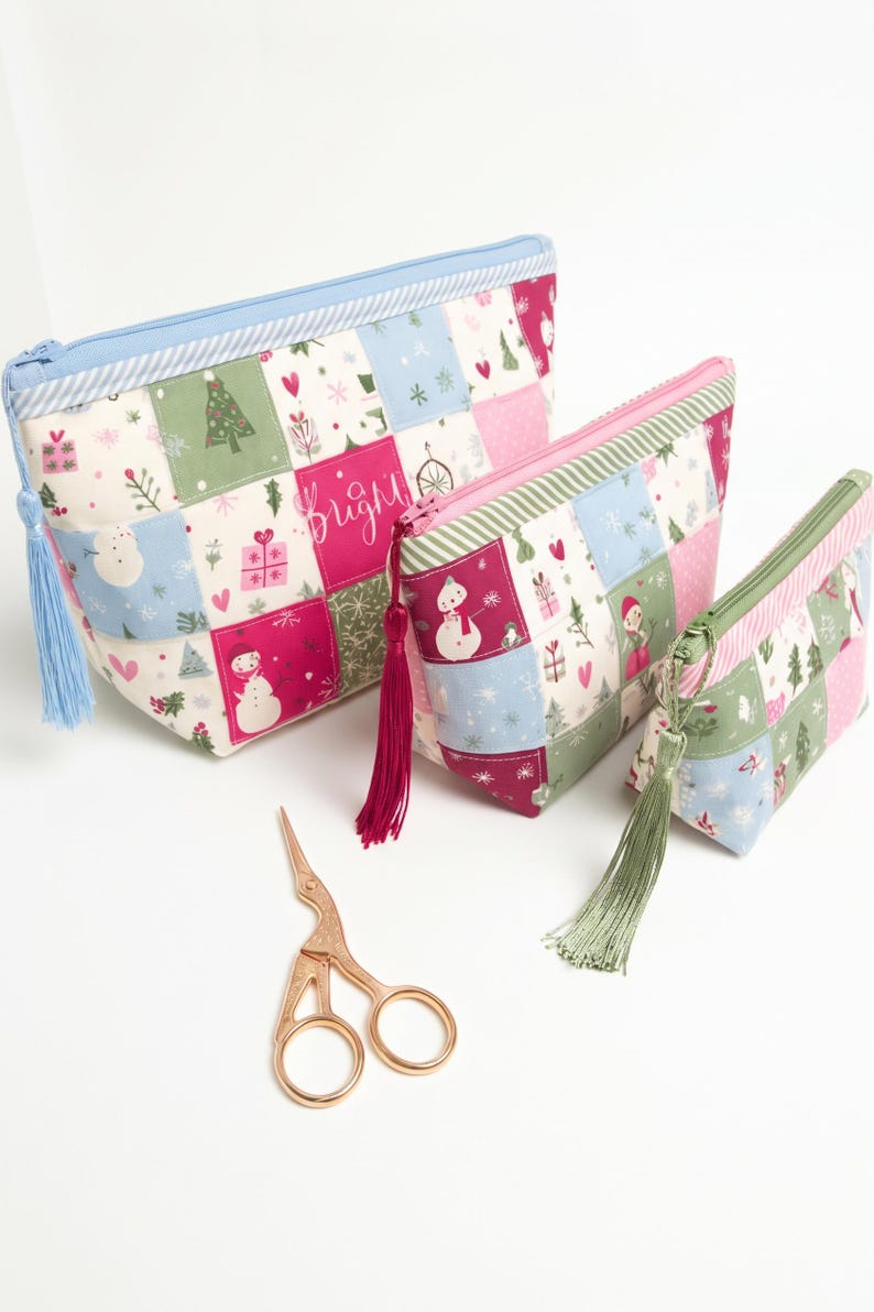 May include: Three zippered pouches in descending sizes featuring a patchwork pattern of snowmen, Christmas trees, and gifts in pink, green, and blue. Each pouch has a matching tassel and a pair of rose gold stork-shaped embroidery scissors.