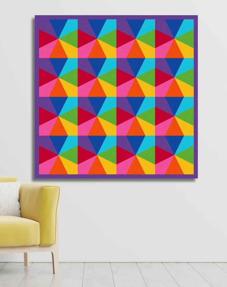 Kaleidoscope quilt pattern in rainbow colors hanging on the wall in front of a yellow velvet chair