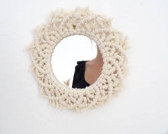 Peut inclure: Un miroir rond avec un cadre en macramé blanc. Le cadre est orné d'une frange sur le pourtour.