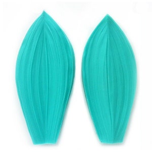 May include: Two turquoise silicone molds shaped like flower petals with a ribbed texture.