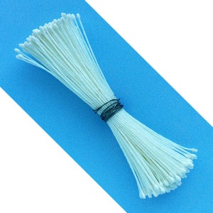 May include: A bundle of white flower stamens, tied together with a thin wire, on a blue background.