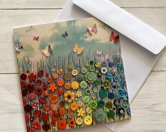 May include: A colourful card featuring a rainbow of buttons arranged in a field of flowers. Butterflies are flying around the field. The card has a light blue background with white clouds.
