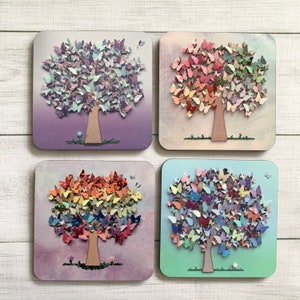 May include: Four square wooden plaques with a painted background and a tree made of butterflies. The trees are different colors: purple, pink, rainbow, and blue.