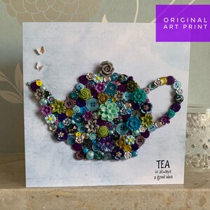 May include: A white card featuring a blue and green teapot crafted from buttons. The teapot is surrounded by small white butterflies. The text "TEA is always a good idea" is printed at the bottom of the card.