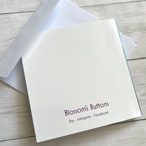 May include: A white card with a purple text that reads "Blossom's Buttons" and "Etsy - Instagram - Facebook".