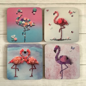 May include: Four coasters featuring pink and purple flamingos made of buttons. The flamingos are on a white background with a pink, blue, or purple gradient.