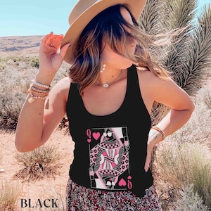 K&ouml;nnte beinhalten: Schwarzes Tanktop mit einem Grafikdruck der Spielkarte der Herzdame. Die Dame tr&auml;gt eine Sonnenbrille und ein rosa Kleid mit einem schwarz-wei&szlig;en Muster. Die Karte ist von rosa Herzen umgeben.