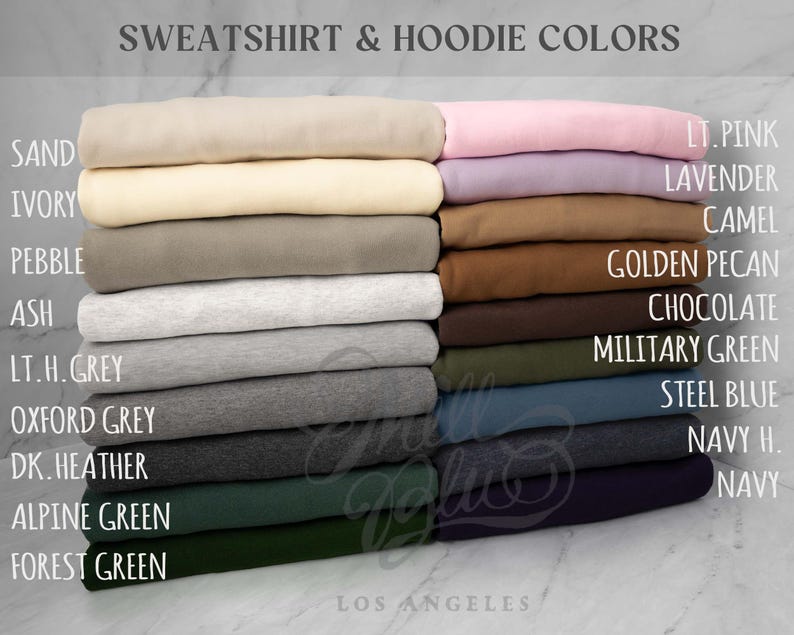 May include: A color chart titled SWEATSHIRT & HOODIE COLORS displaying folded fabric stacks in shades of sand, ivory, pebble, ash, light heather grey, oxford grey, dark heather, alpine green, forest green, light pink, lavender, camel, golden pecan, chocolate, military green, steel blue, navy heather, and navy.