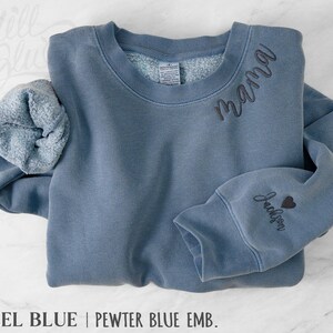 May include: Steel blue sweatshirt with the word "mama" embroidered on the chest and "Jackson" with a heart on the sleeve. The sweatshirt has a crew neck and a soft, fleecy interior.