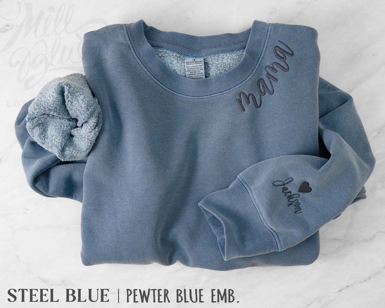 May include: Steel blue sweatshirt with the word "mama" embroidered on the chest and "Jackson" with a heart on the sleeve. The sweatshirt has a crew neck and a soft, fleecy interior.