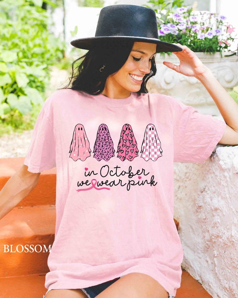May include: Pink t-shirt with four ghosts wearing different pink patterns. The text "in October we wear pink" is below the ghosts with a pink ribbon.