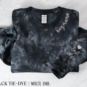 May include: Black tie-dye sweatshirt with white embroidered text reading "boy mama" on the upper right chest and "Emytt Myles" on the left sleeve. A small silver heart is embroidered next to the names. The bottom of the image reads "BLACK TIE-DYE | WHITE EMB."