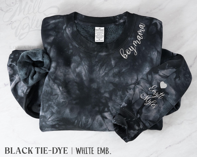 May include: Black tie-dye sweatshirt with white embroidered text reading "boy mama" on the upper right chest and "Emytt Myles" on the left sleeve. A small silver heart is embroidered next to the names. The bottom of the image reads "BLACK TIE-DYE | WHITE EMB."