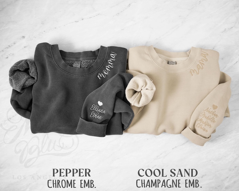 May include: Two crewneck sweatshirts, one dark grey and one beige, with embroidered text. The dark grey sweatshirt has "momma" on the collar and "Elliana Ethan" on the sleeve. The beige sweatshirt has "mama" and names on the sleeve.