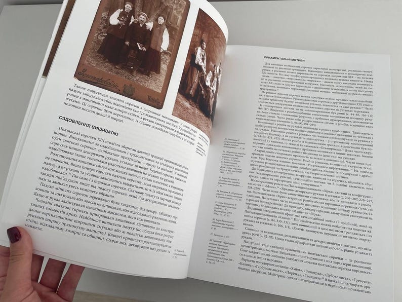 May include: A book open to a page with a black and white photo of a group of people. The text on the page is in Ukrainian and discusses the history of Ukrainian embroidery.