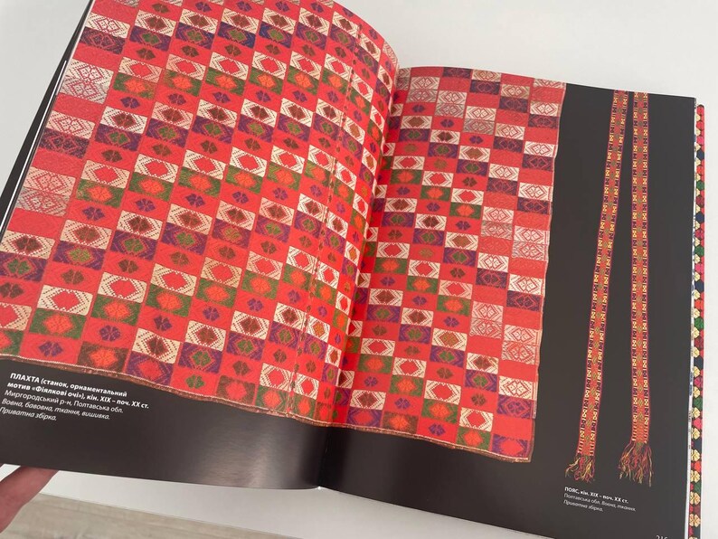 May include: A red and white checkered fabric with a geometric pattern. The fabric is woven with different colored threads, including red, white, green, and purple. The fabric is displayed on a book with the text "PLAHTA (blanket) - ethnic, ornamental, motif "Afghanskiy uzol" (Afghan knot), XIX - XX cc.  The fabric is made in the village of "Kishlak" (village) in the "Kishlak" (village) district of the "Kishlak" (village) region.  The fabric is made of wool and cotton.  The fabric is used for blankets, rugs, and other household items.  The fabric is a traditional Afghan textile.