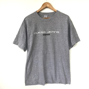 May include: A grey short-sleeved t-shirt with the text "Guess Jeans USA" printed in white on the front.