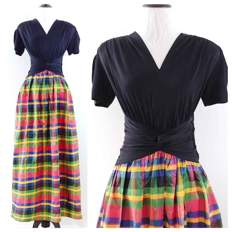 May include: A black short-sleeved dress with a v-neck and a knotted waist. The skirt is a colorful plaid pattern with red, yellow, green, and blue.
