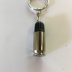 May include: A silver bullet keychain with a black rubber top. The keychain has a silver ring and chain.