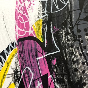 Op de afbeelding: Close-up van een abstract schilderij. Het kunstwerk maakt gebruik van gedurfde penseelstreken in zwart, wit, geel en roze. Witte lijnen en vormen overlappen de kleurrijke achtergrond. Het schilderij heeft een textuur.