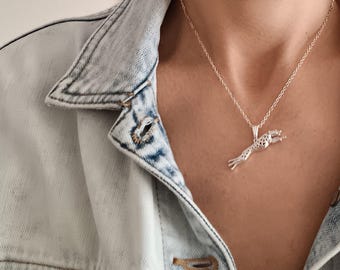 Puede incluir: Un collar de cadena de plata con un colgante de plata detallado de un guepardo saltando.