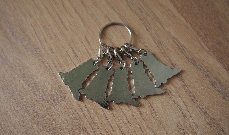 May include: A silver key chain with six silver charms shaped like dogs. The charms are attached to a silver ring.