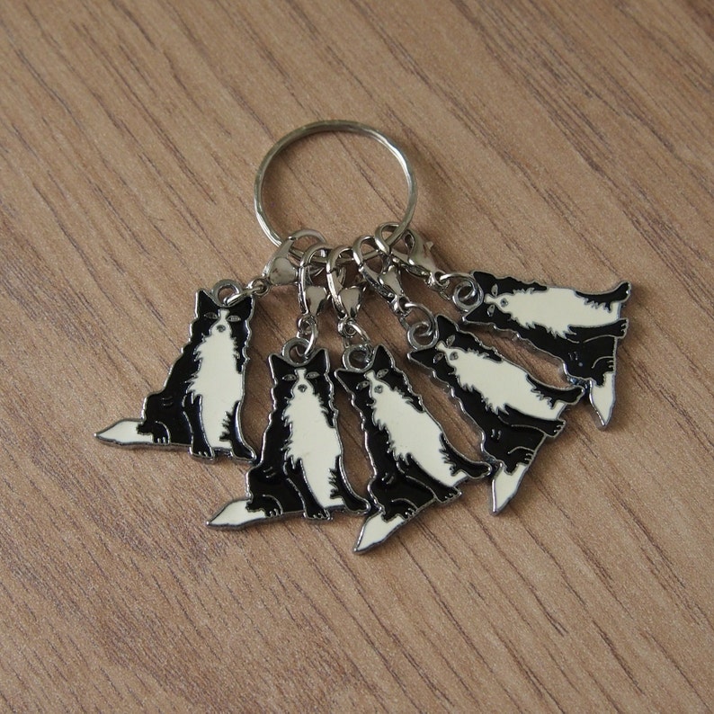 May include: A set of six black and white dog charms with silver rings. The charms are attached to a silver key ring.