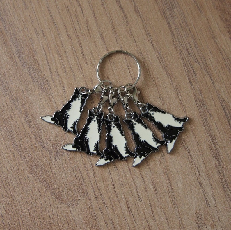 May include: A silver key chain with six black and white dog charms. Each charm features a different pose of a dog.