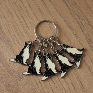 May include: A silver key chain with six black and white cat charms. The charms are attached to a silver ring and have a silver lobster clasp.