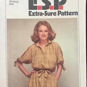 May include: Simplicity pattern number 8823, an Extra-Sure Pattern for a dress, size K (8, 10, 12) Miss. The pattern shows a woman wearing a plaid dress with a tie belt.