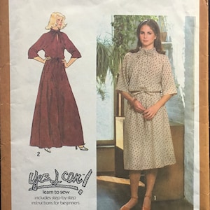 May include: Simplicity sewing pattern number 8741 for a dress. The pattern is for size 10 and includes instructions for beginners. The pattern shows two different styles of dresses, one with a long skirt and one with a shorter skirt. Both dresses have a high neck and a tie at the waist.