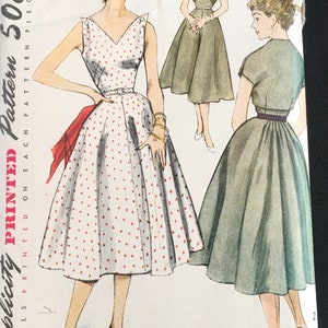 May include: Vintage Simplicity sewing pattern for a dress, size 14, bust 32. The pattern shows two different styles of dresses, one with polka dots and one with a solid color. The pattern is printed on a white background with black text.