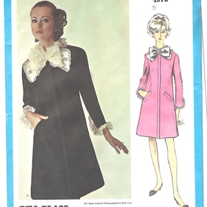 Peut inclure: Un patron de couture Vogue Americana vintage de 1973 pour un modèle de manteau Bill Blass. Le patron présente deux styles de manteaux différents, l'un noir avec un col et des poignets en dentelle blanche, et l'autre rose avec un nœud au col.