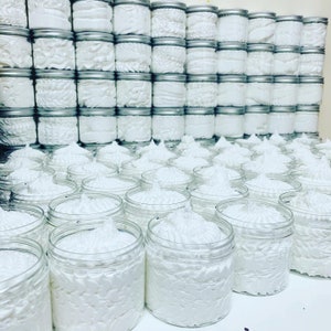 May include: A large collection of white whipped body butter in clear plastic jars with silver lids. The jars are arranged in rows and columns, creating a visually appealing display.