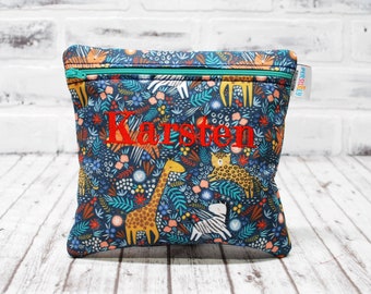 May include: A blue zippered pouch with a colorful jungle animal print and the name "Karsten" embroidered in red.