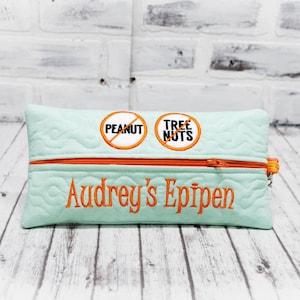 May include: A light blue zippered pouch with the words "Peanut" and "Tree Nuts" with a diagonal line through them. The pouch also has the name "Audrey's EpiPen" embroidered on it.