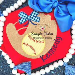 May include: Red baseball themed embroidered design with a brown and yellow baseball glove, a yellow baseball, and a blue and white checkered bow. The text "Sawyers Charm Embroidery Designs" and "Kennedy" are embroidered in black.