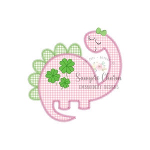 May include: Pink and green embroidered applique of a dinosaur with four-leaf clovers on its back. The dinosaur has a green bow on its head and closed eyes. The text "Sawyer's Charm Embroidery Designs" is below the dinosaur.