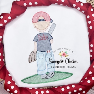 May include: Embroidered design of a baseball player with a red hat, blue shirt, and blue jeans. The player is holding a baseball bat and a glove. The design includes the name "Luke" on the shirt and the text "Sawyers Charm Embroidery Designs" below.