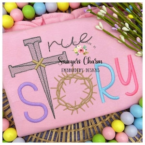 May include: Pink embroidered shirt with the words "His Story" in colorful letters. The design includes a cross with nails, a crown of thorns, and the text "Sawyers Charm Embroidery Designs".
