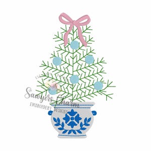 May include: An embroidered design of a Christmas tree with light blue ornaments and a pink bow. The tree is in a blue and white decorative pot. The text "Sawyers Charm Embroidery Designs" is also included.