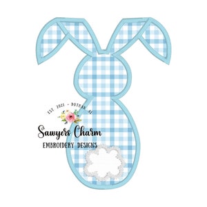 May include: A blue and white gingham bunny applique embroidery design. The design features a bunny with long ears and a small flower detail. The text "Sawyers Charm Embroidery Designs" is included in the design.