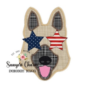 May include: A brown and tan German Shepherd dog face with a red, white, and blue star on each eye. The dog's nose is black, and the tongue is pink. The background is a tan burlap fabric.