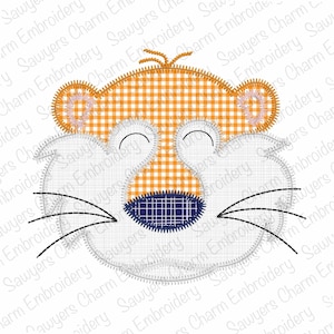 May include: A whimsical tiger face design, featuring a white face with black whiskers and a blue nose. The tiger's head is orange and white checkered, with orange ears and a stitched outline. This design is suitable for embroidery projects.